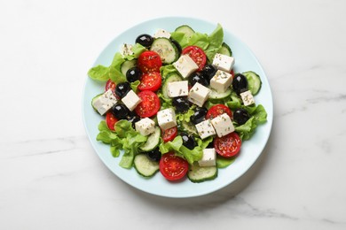 Delicious salad with feta cheese on white marble table, top view