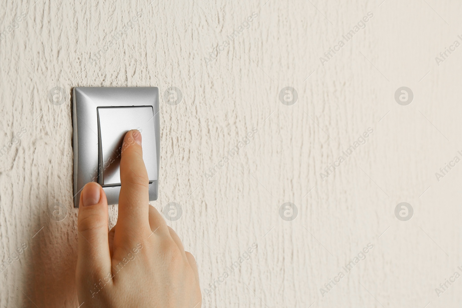 Photo of Woman turning light switch on, closeup view