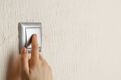 Photo of Woman turning light switch on, closeup view