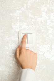 Photo of Woman turning light switch on, closeup view