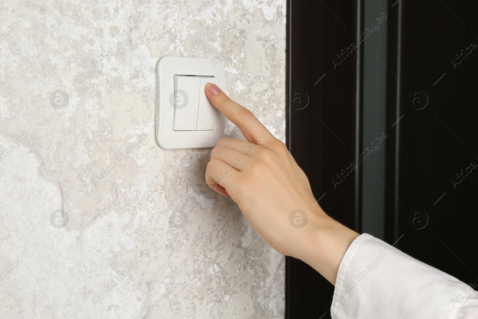 Photo of Woman turning light switch on, closeup view