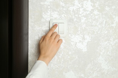 Photo of Woman turning light switch on, closeup view