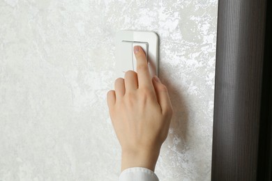 Photo of Woman turning light switch on, closeup view