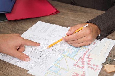 Real estate agent working with client at wooden table, closeup