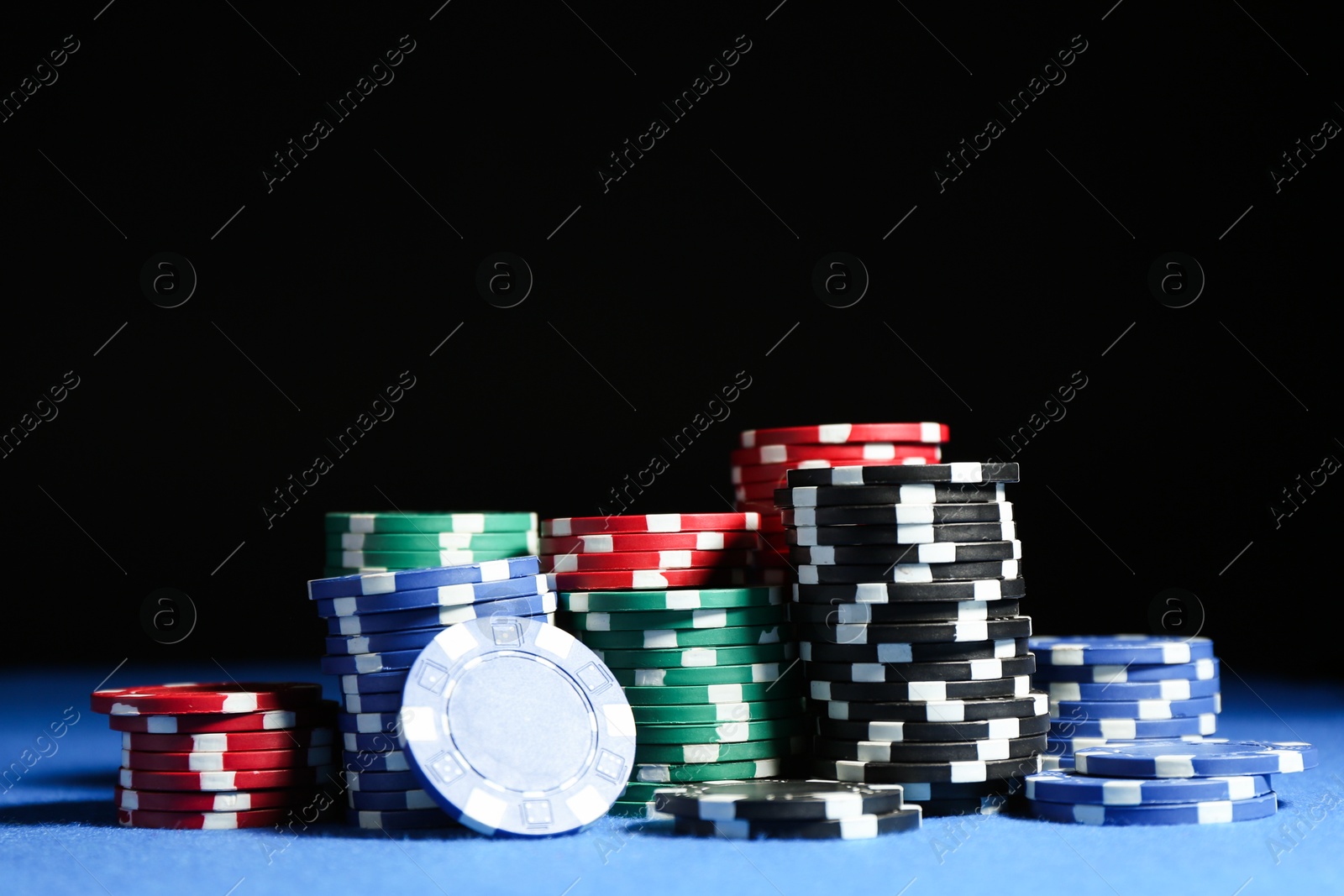 Photo of Poker game. Casino chips on blue table against dark background