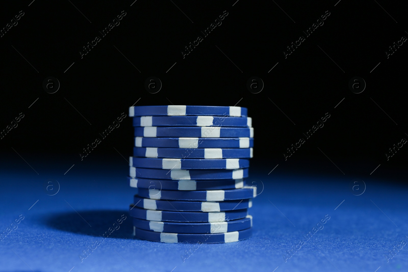 Photo of Poker game. Casino chips on blue table against dark background