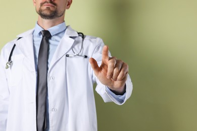 Photo of Doctor pointing at something on olive background, closeup