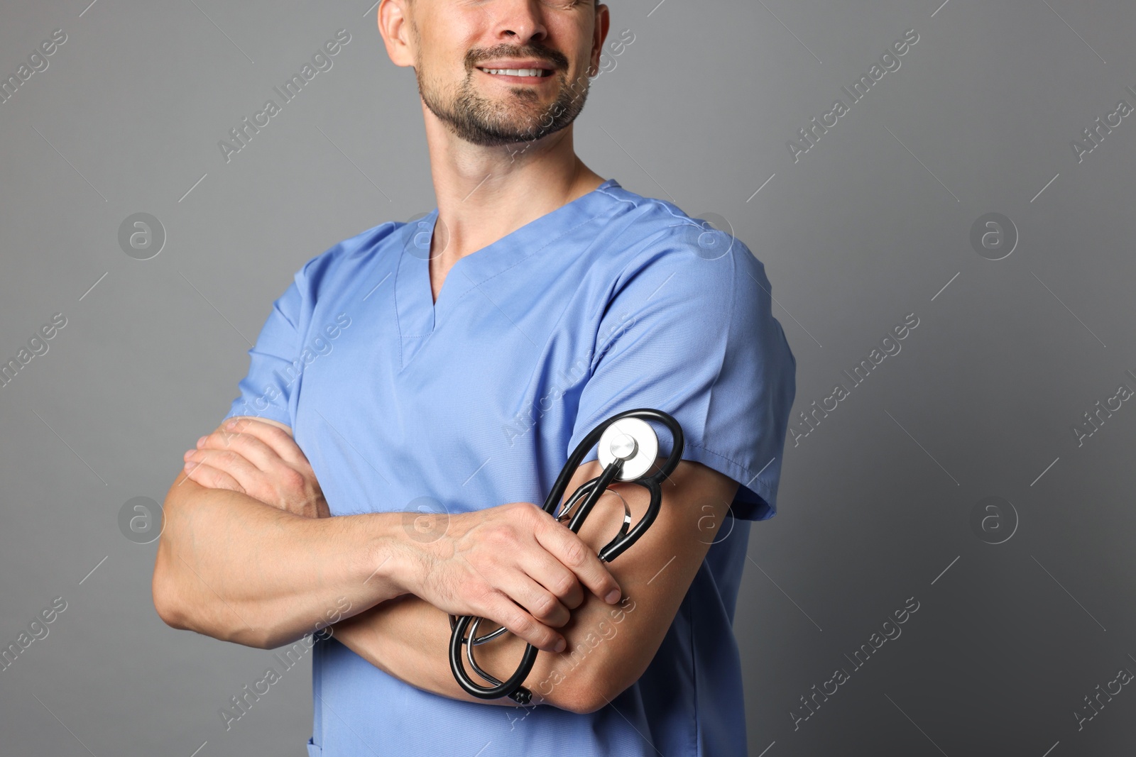 Photo of Nurse with stethoscope on grey background, closeup