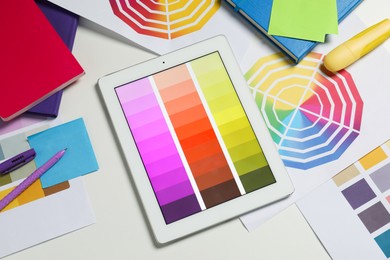 Photo of Designer's workplace with tablet, different palettes and stationery on white table, flat lay