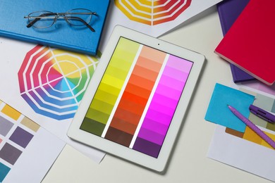 Photo of Designer's workplace with tablet, different palettes and stationery on white table, flat lay