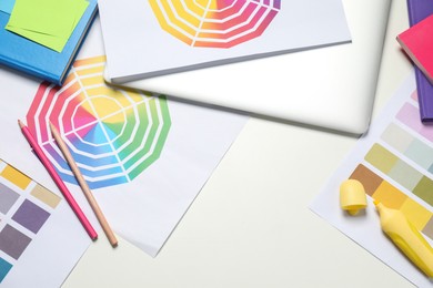 Photo of Designer's workplace with laptop, different palettes and stationery on white table, flat lay