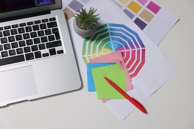 Photo of Designer's workplace with laptop and palettes on white table, flat lay