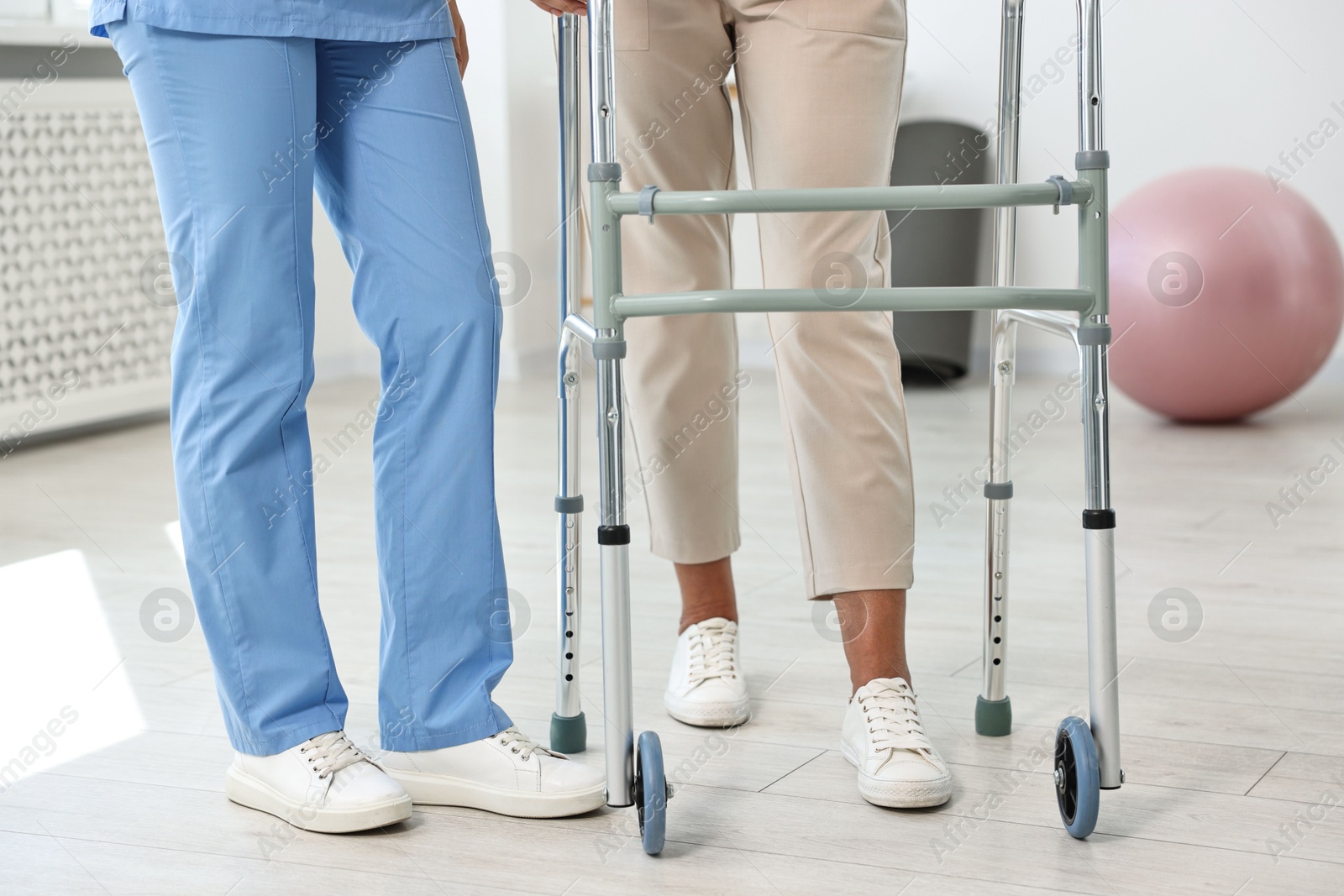 Photo of Nurse near senior woman with walking frame in clinic, closeup