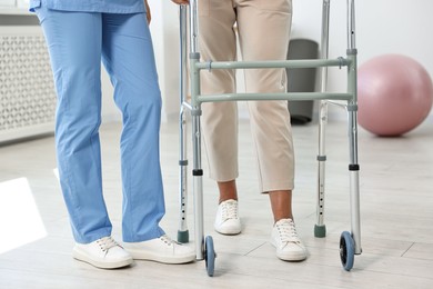 Photo of Nurse near senior woman with walking frame in clinic, closeup