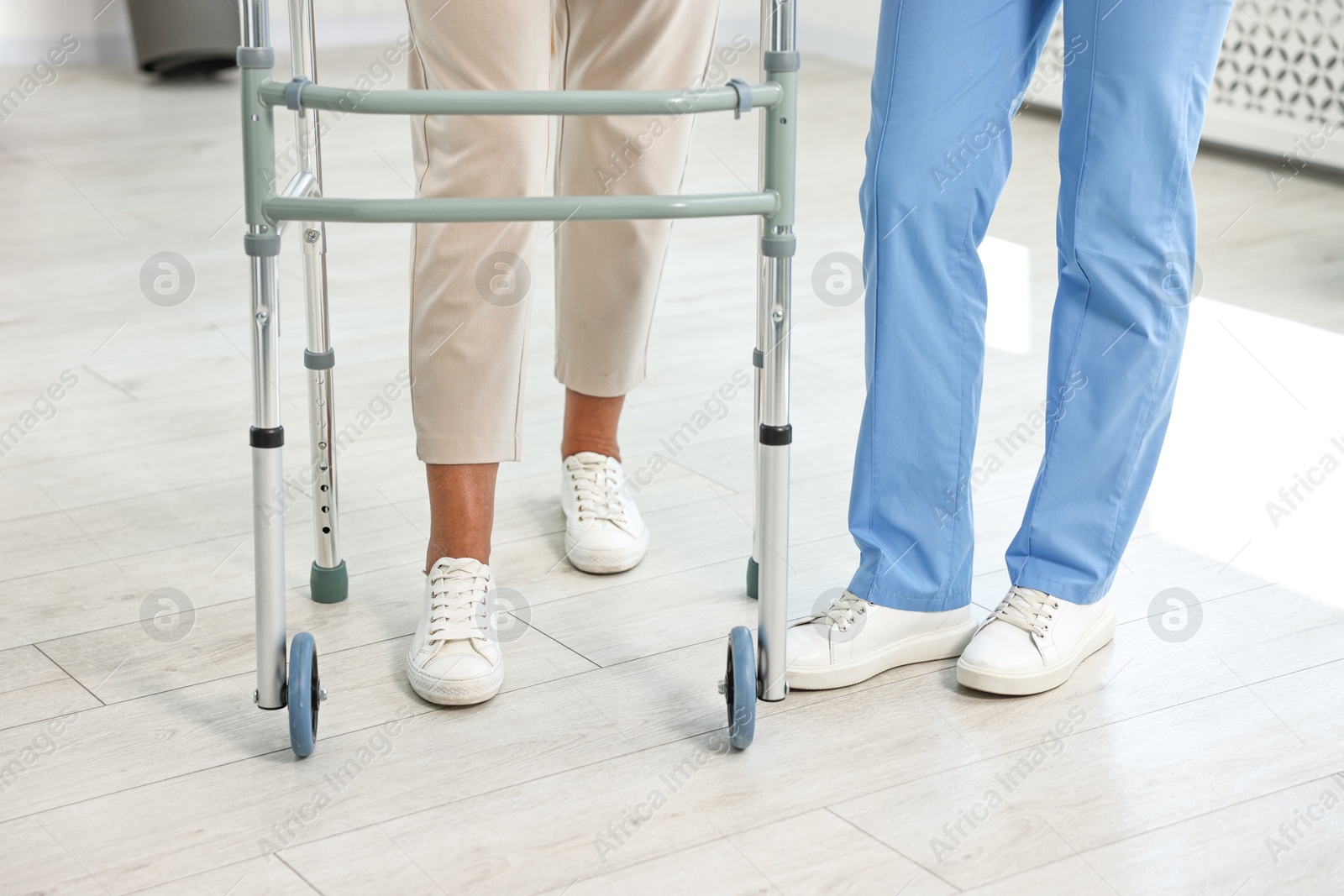 Photo of Nurse near senior woman with walking frame in clinic, closeup