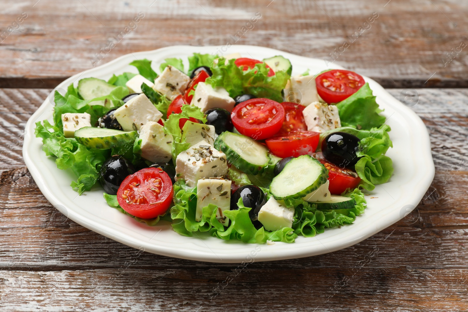 Photo of Delicious salad with feta cheese on wooden table, closeup