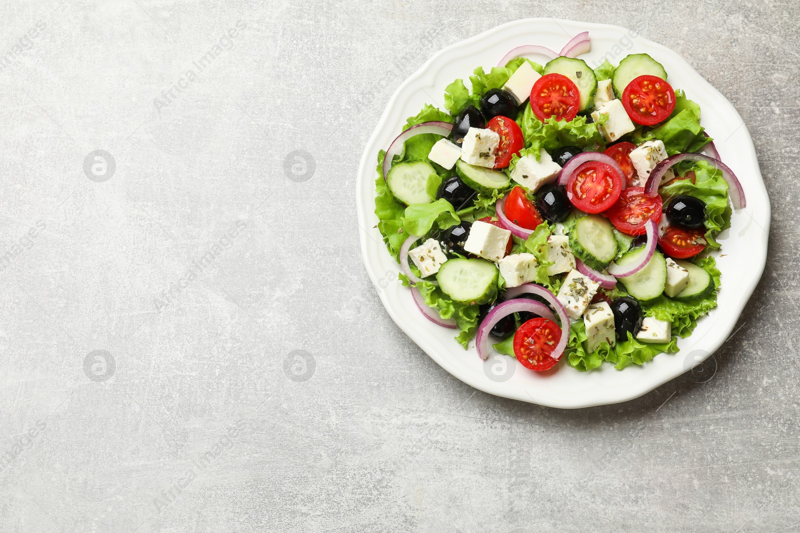 Photo of Delicious salad with feta cheese on gray textured table, top view. Space for text