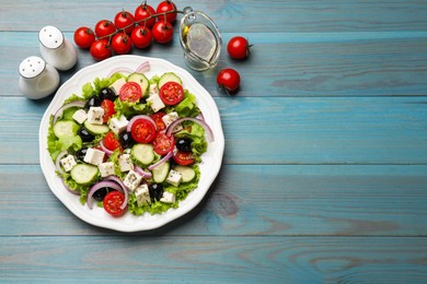 Photo of Delicious salad with feta cheese and ingredients on light blue wooden table, flat lay. Space for text