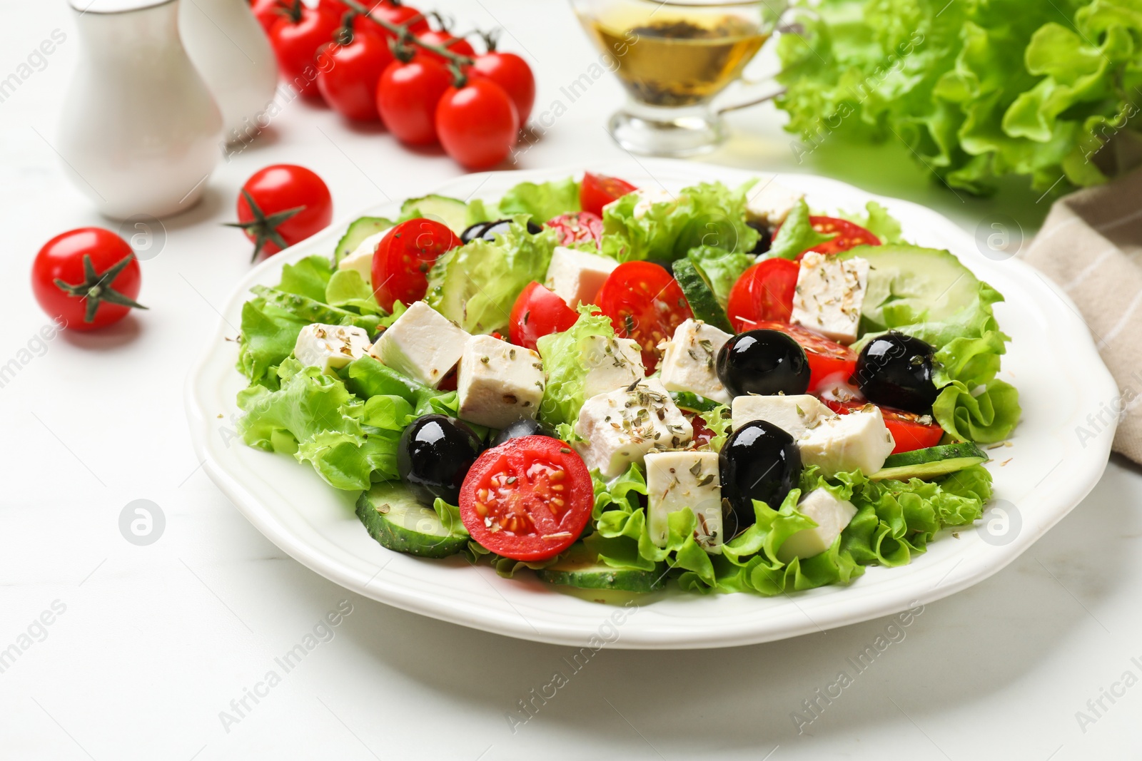 Photo of Delicious salad with feta cheese and ingredients on white table, closeup