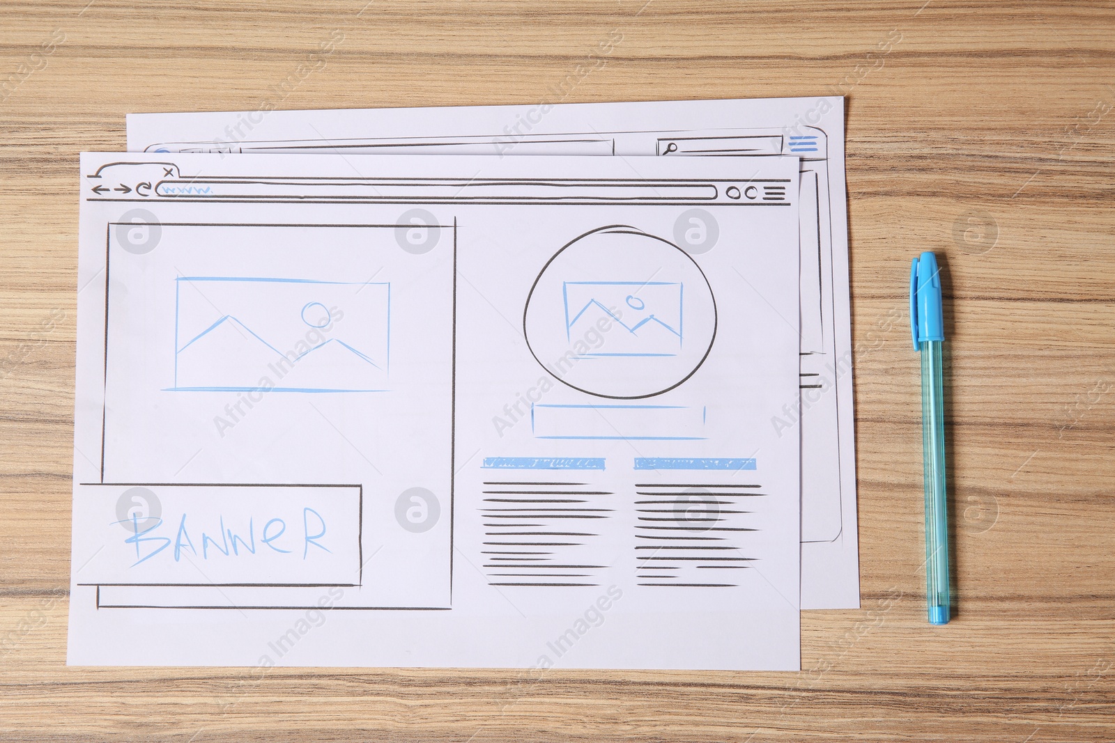 Photo of Website development. Sketches of wireframes and pen on wooden table, flat lay