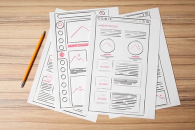 Website development. Sketches of wireframes and pencil on wooden table, flat lay