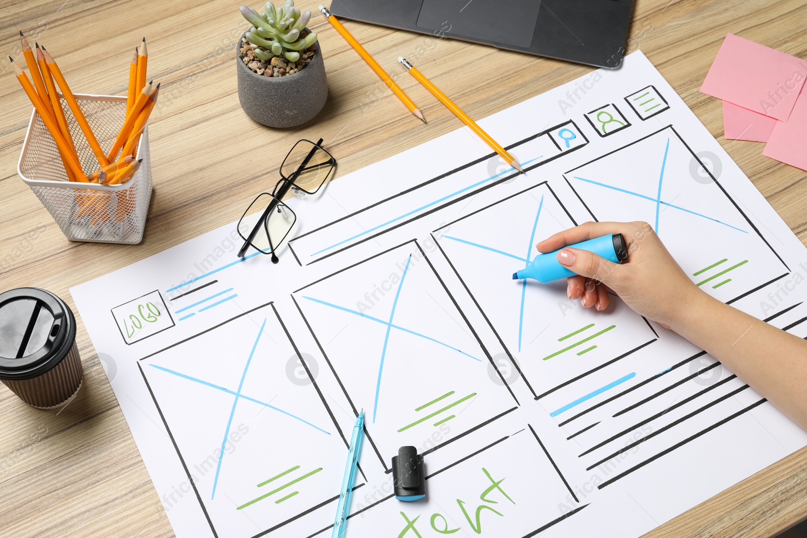 Photo of Website designer creating wireframe on paper with highlighter at wooden table, closeup