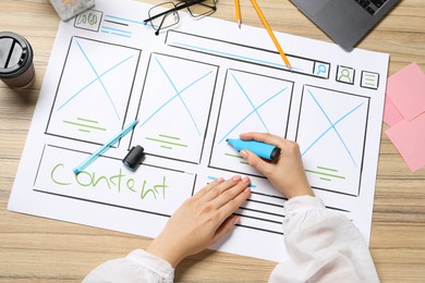 Website designer creating wireframe on paper with highlighter at wooden table, top view