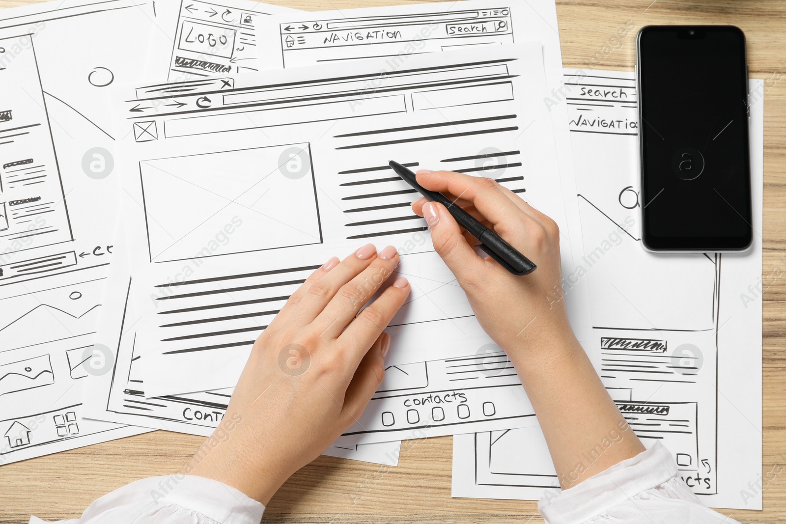 Photo of Website designer creating wireframe on paper with pen at wooden table, top view