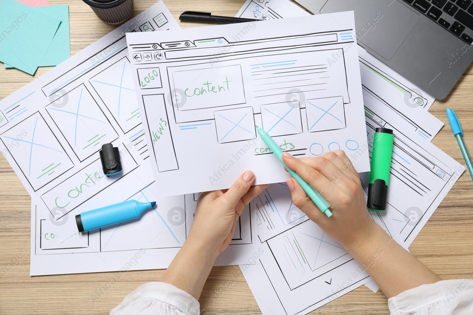 Photo of Website designer creating wireframe on paper with pen at wooden table, top view