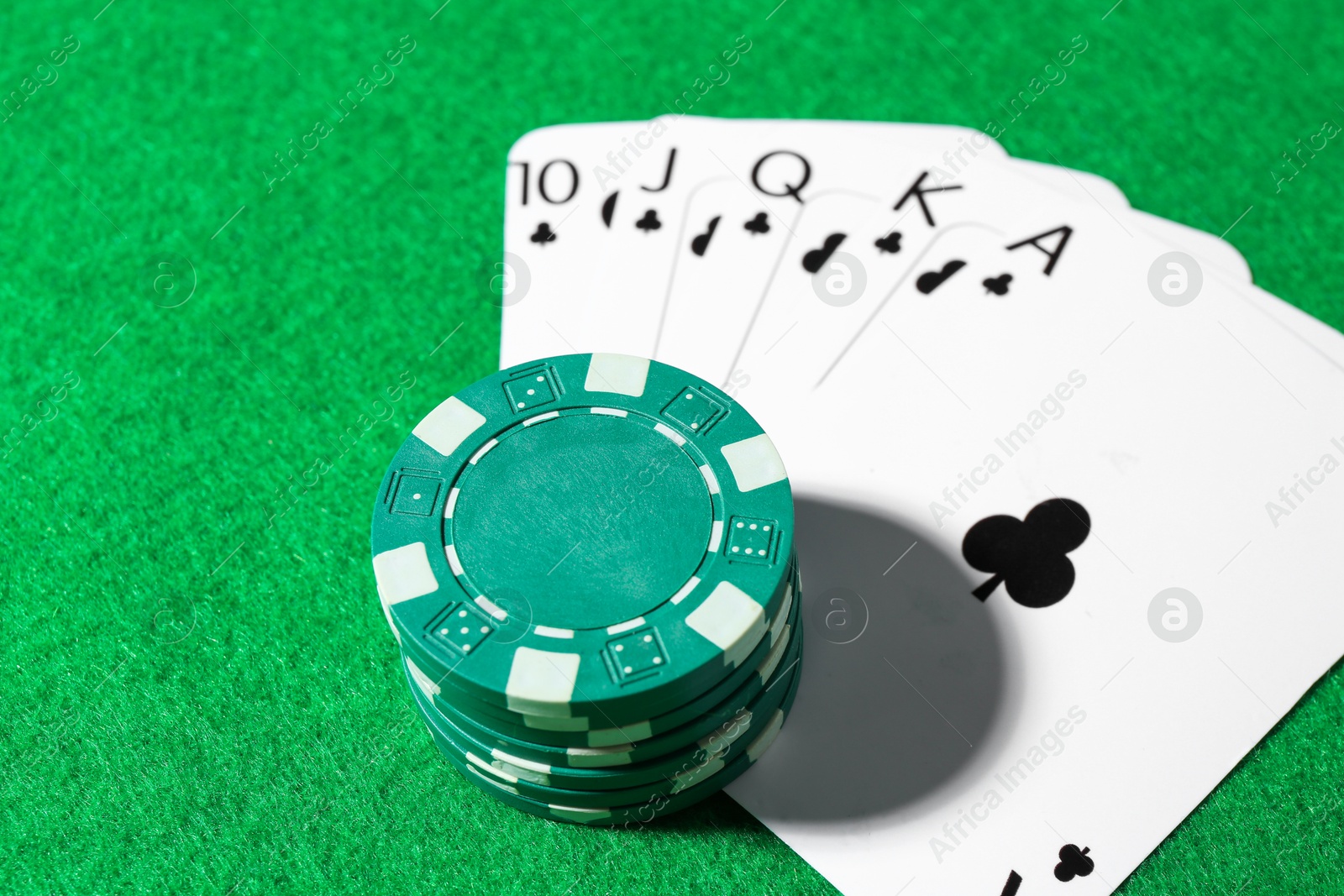 Photo of Playing cards and poker chips on green table, closeup