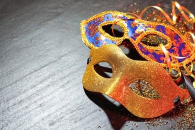 Photo of Beautiful carnival masks on gray textured table, closeup. Space for text