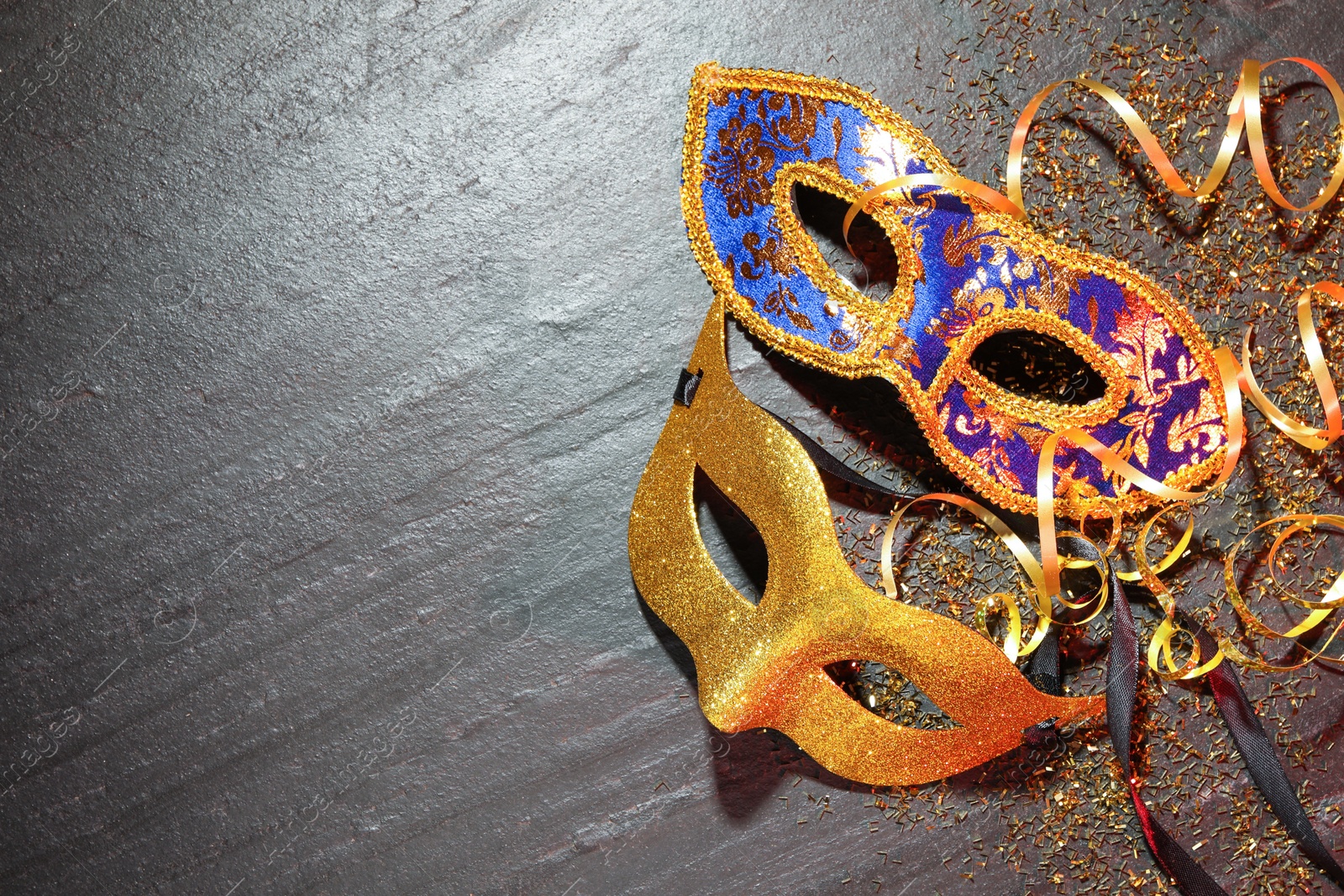 Photo of Beautiful carnival masks and confetti on gray textured table, flat lay. Space for text