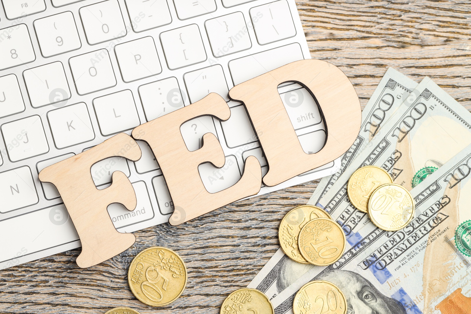 Photo of Word Fed (Federal Reserve System) made with letters, keyboard, dollar banknotes and coins on wooden table, flat lay