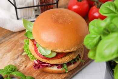 Photo of Delicious vegan burger with chickpea cutlet on white tiled table, closeup