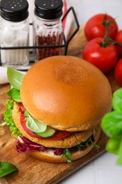 Photo of Delicious vegan burger with chickpea cutlet on white tiled table, closeup