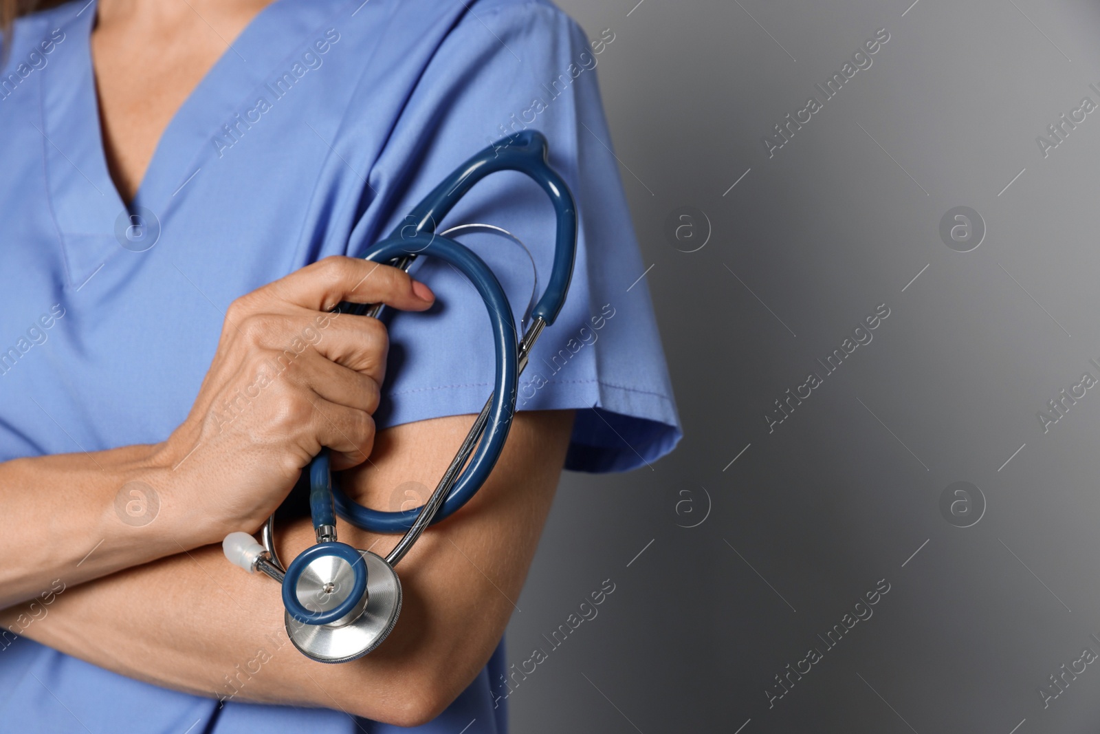 Photo of Doctor with stethoscope on gray background, closeup. Space for text