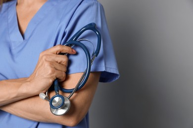 Photo of Doctor with stethoscope on gray background, closeup. Space for text