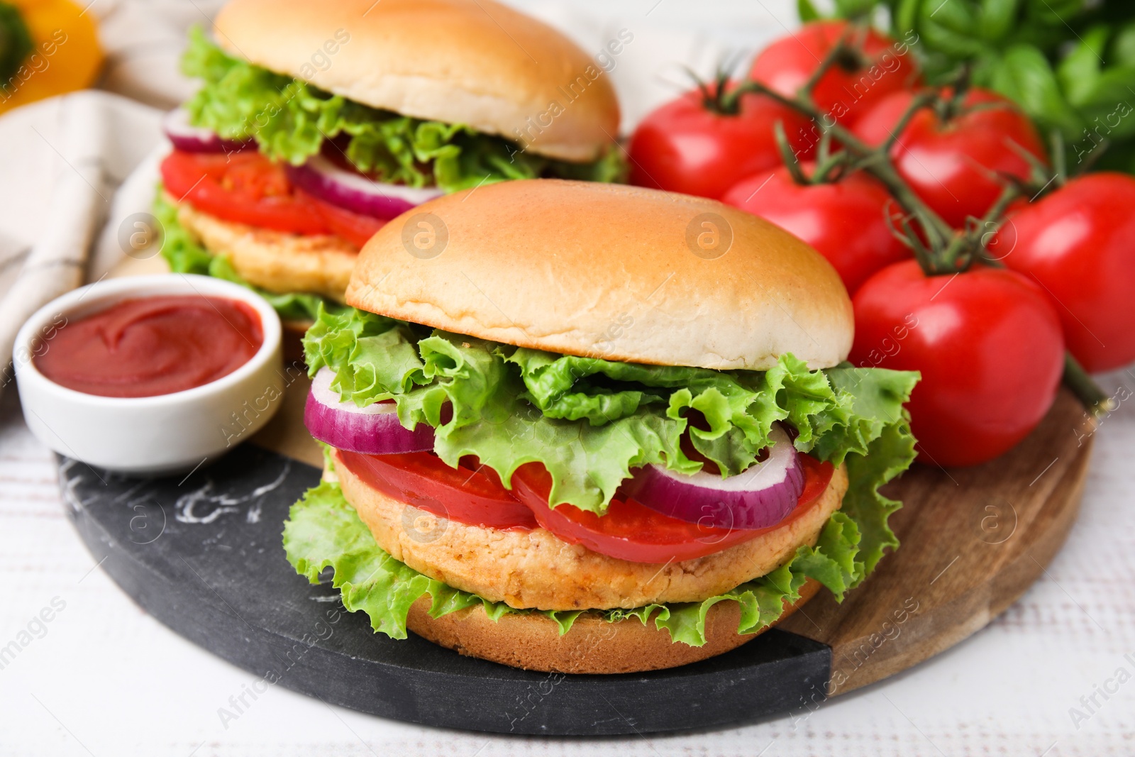 Photo of Delicious vegetarian burgers with chickpea cutlets, tomatoes and sauce on white table, closeup