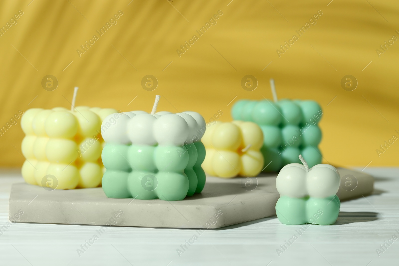 Photo of Beautiful bubble candles on white wooden table, closeup