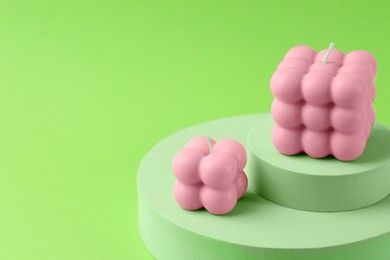 Photo of Beautiful pink bubble candles and podiums on green background, closeup. Space for text