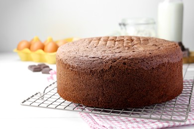 Photo of Tasty chocolate sponge cake and ingredients on white wooden table, closeup