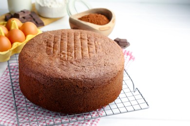 Photo of Tasty chocolate sponge cake and ingredients on white wooden table, closeup