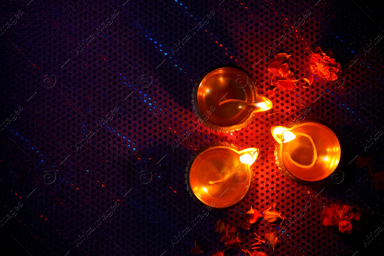 Photo of Diwali celebration. Diya lamps and beautiful flowers on dark background, top view. Space for text