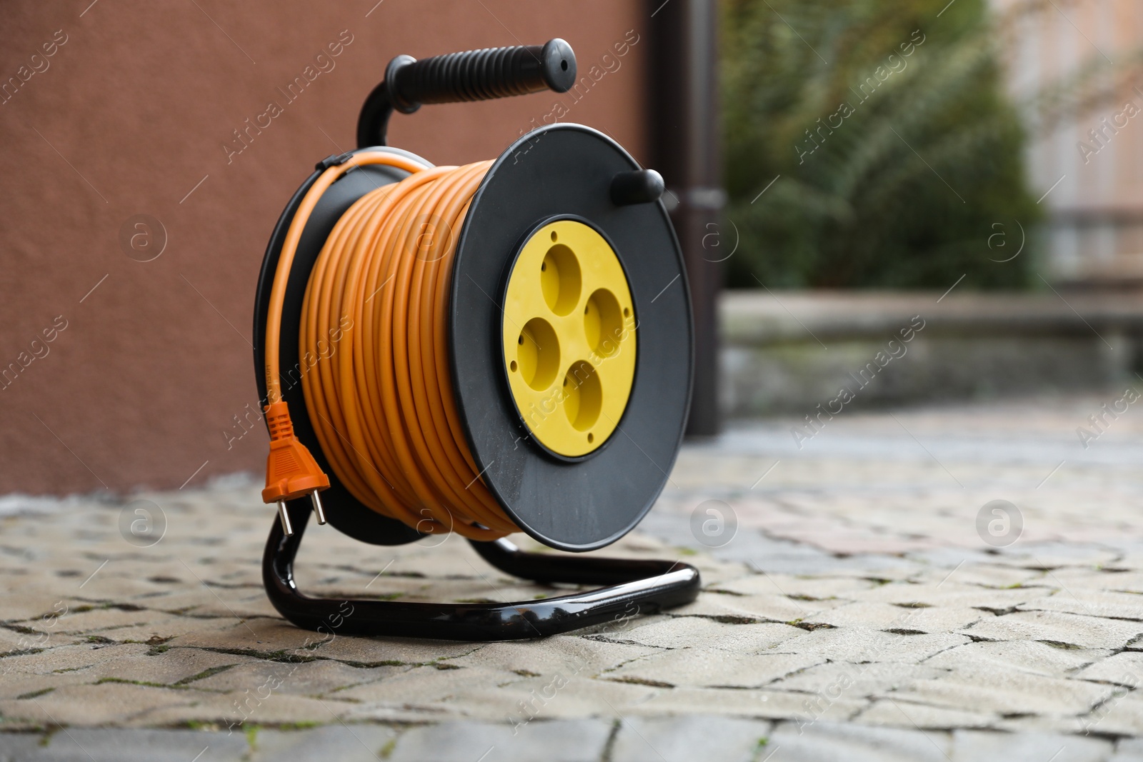 Photo of One extension cord reel on pavement outdoors, space for text