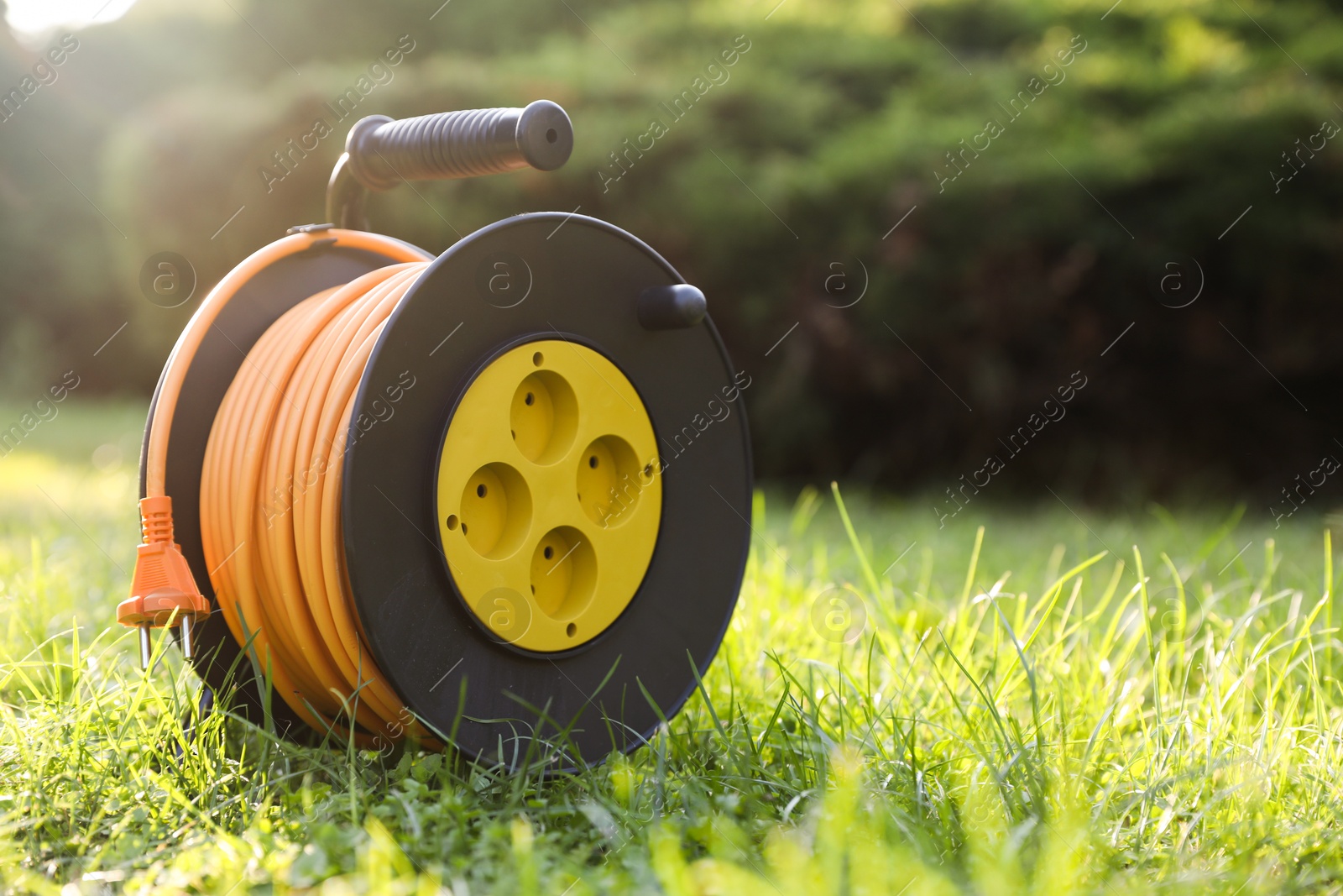 Photo of One extension cord reel on green grass outdoors, space for text