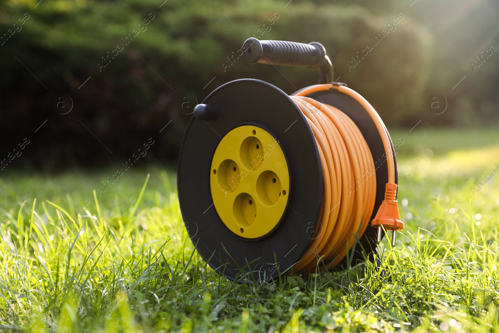 Photo of One extension cord reel on green grass outdoors, space for text