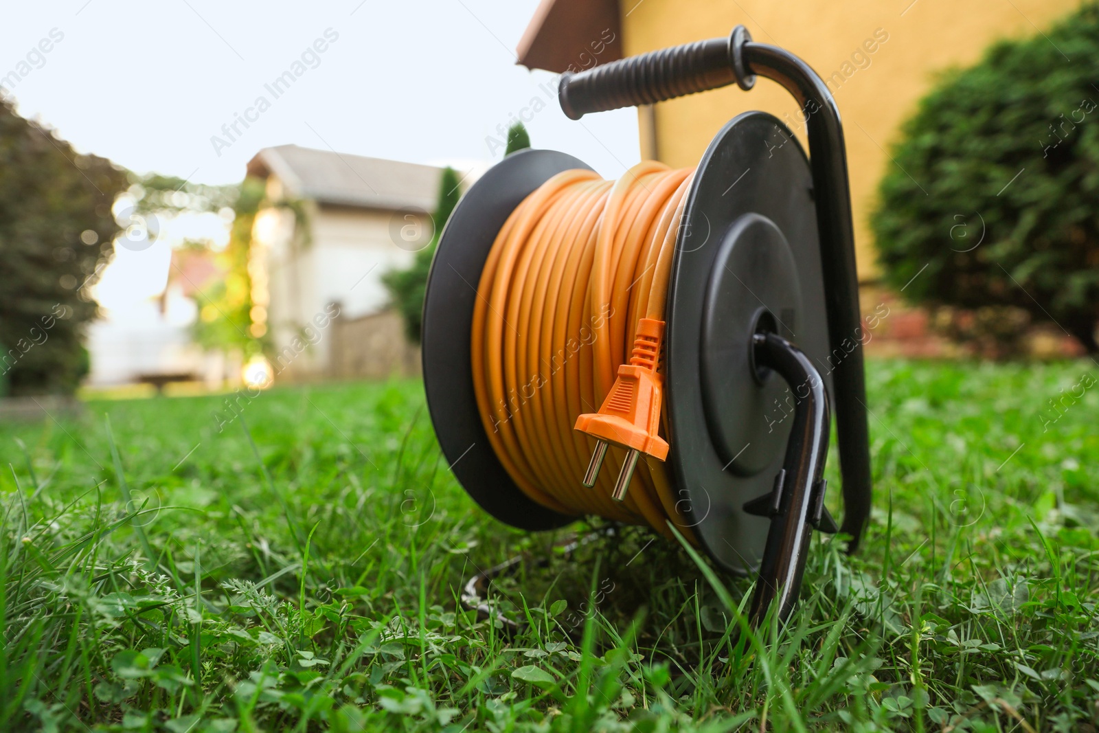 Photo of One extension cord reel on green grass outdoors, space for text