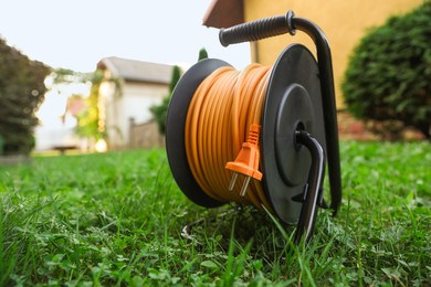 One extension cord reel on green grass outdoors, space for text