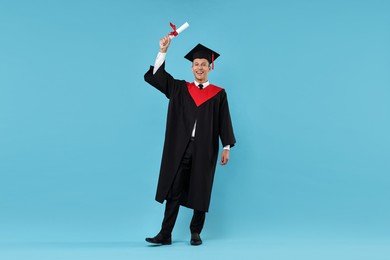 Photo of Happy student with diploma after graduation on light blue background