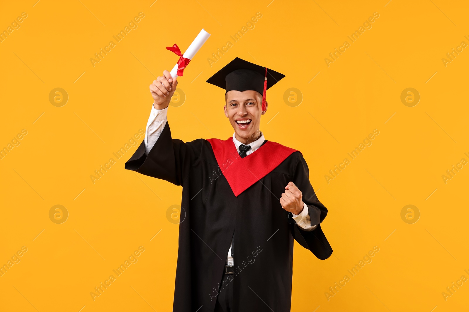 Photo of Happy student with diploma after graduation on orange background